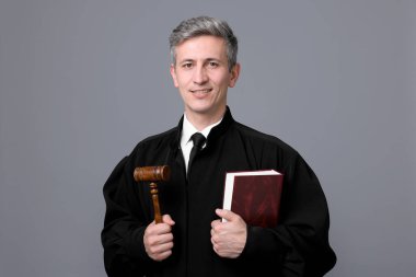 Çekiç ve gri arka plan kitabı ile gülümseyen yargıç