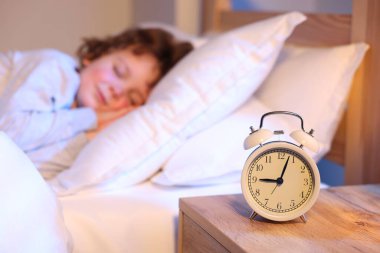 Evde uyuyan küçük çocuk, çalar saate odaklan.