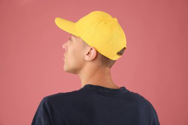 Pembe arka planda şık bir beyzbol şapkası takan genç adam.