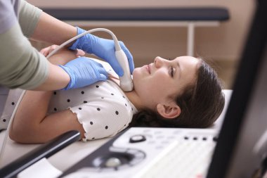 Sonograf, klinikte kızın tiroid bezi ultrason muayenesini yönetiyor.