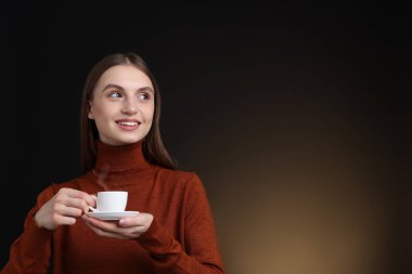 Kahverengi arka planda bir fincan kahveyle gülümseyen kadın. Metin için boşluk