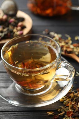 Bitki çayı ve kuru yaprakları siyah ahşap masada serinletiyor.