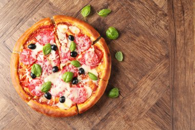 Tahta masada salamlı, peynirli, fesleğenli ve zeytinli lezzetli pizza. Metin için boşluk