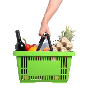 Beyaz arka planda farklı ürünleri olan alışveriş sepeti tutan adam, yakın plan.