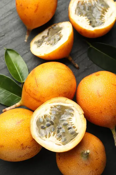 Olgun tutku meyveleri ve yeşil yapraklar siyah masanın üzerinde, düz yatıyordu.