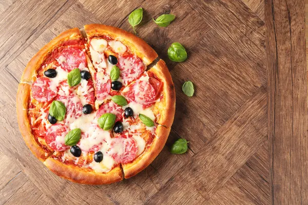 Tahta masada salamlı, peynirli, fesleğenli ve zeytinli lezzetli pizza. Metin için boşluk