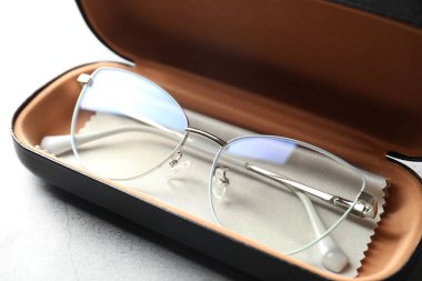 Şık gözlüklü çanta ve gri masadaki temizlik bezi, yakın plan.