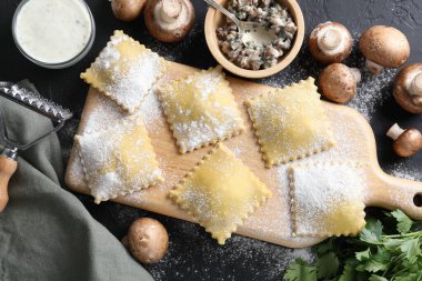 Pişmemiş ravioli, mantar ve sos siyah masada, düz yatıyordu.