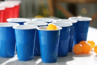 Plastik bardaklar, alkollü içecekler ve açık ahşap masada bulanık ışıklara karşı toplar, yakın çekim. Bira pong oyunu