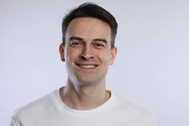 Açık gri arka planda gülümseyen adamın portresi, yakın plan.