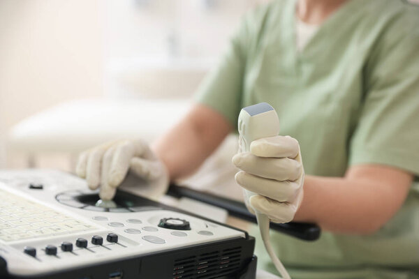 Professional sonographer with ultrasound machine in clinic, closeup