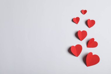 Açık gri arkaplanda bir sürü kağıt kalp, düz bir zemin. Metin için boşluk