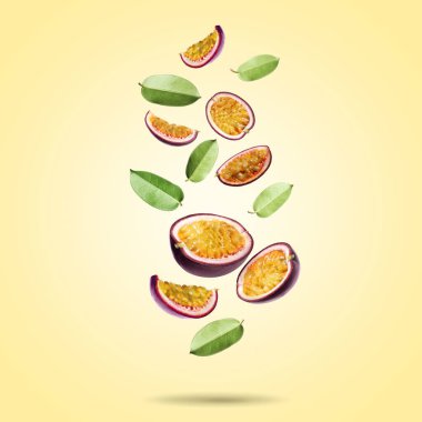 Nefis kesilmiş tutku meyveleri ve yeşil yapraklar soluk sarı eğimli arka plana dökülüyor.