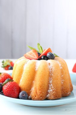 Beyaz ahşap masada pudra şekeri ve böğürtlenli Lezzetli kek, yakın plan. Metin için boşluk