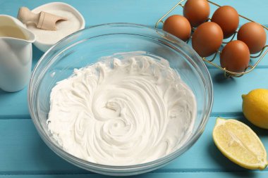 Krem şanti kasede, yumurta ve diğer ürünler açık mavi ahşap masada, yakın plan