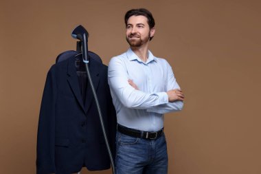 Kahverengi arka planda vapuru ve ceketi olan adam.