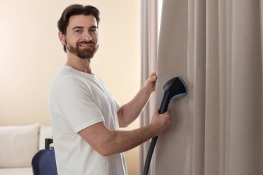 Evde buharlı perdeleri olan bir adam.