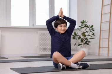 Paspasın üstünde yoga yapan tatlı çocuk.