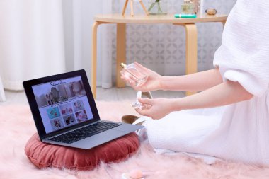 Blogcu dizüstü bilgisayarın yanında parfüm tutuyor moda blogu sitesi içeride, yakın plan