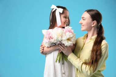 Anne ve kızı bir buket güzel şakayıkla açık mavi arka planda, mesaj için yer var.