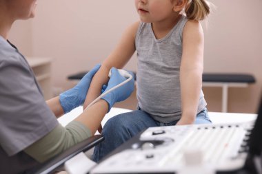Sonograf, klinikte küçük bir kızın kolunun ultrason muayenesi yapıyor.