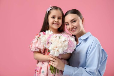 Anne ve kızı pembe arka planda bir buket güzel şakayıkla