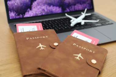 Pasaportlar, uçuş biletleri, uçak modeli ve laptop ahşap masada, yakın plan.
