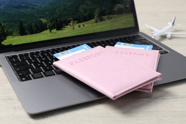 Pasaportlar, uçuş biletleri, uçak modeli ve laptop ahşap masada, yakın plan.