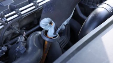 İşçi arabada motor yağı seviyesini dipstick ile kontrol ediyor.