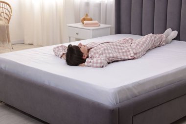 Evdeki yumuşak yatakta uzanan güzel bir kadın.