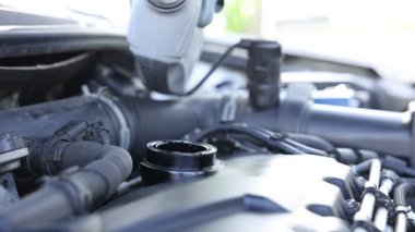 İşçi motor yağını teneke kutudan araba motoruna boşaltıyor.