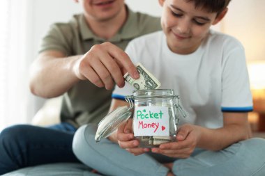 Baba ve oğul evde yataktaki kavanoza cep harçlığı koyuyorlar, seçici bir şekilde.