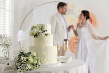 Mutlu evli çift içeride, düğün pastasına ve masadaki bukete odaklan.