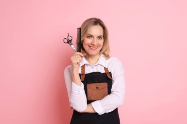 Pembe arka planda tarak ve makasla gülümseyen kuaför.