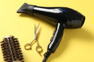 Sarı arka planda farklı saç şekillendirme araçları, yakın plan