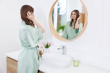 Güzel bir kadın aynada kendine bakıyor.