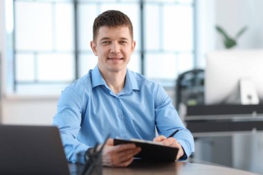 Ofiste masa başında çalışan yakışıklı adam.