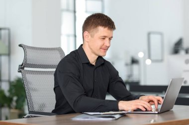 Ofiste masada dizüstü bilgisayarda çalışan adam