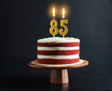 Siyah arka planda yanan mumlar olan lezzetli bir pasta. 85. yaş günü ya da diğer özel günler