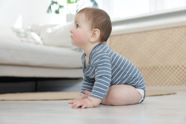 Evde yerde oturan şirin bir bebek.