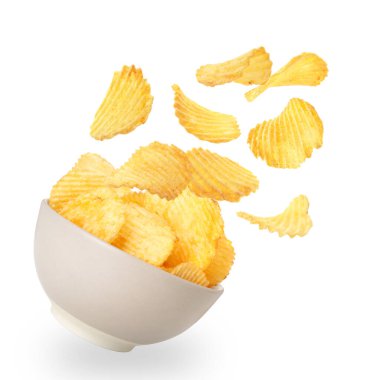 Lezzetli patates cipsleri beyaz arka planda kaseye düşüyor.