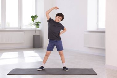 Yoga paspası üzerinde egzersiz yapan tatlı çocuk.