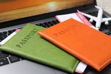 Pasaportlar, uçuş biletleri, uçak modeli ve dizüstü bilgisayar masada, yakın plan.