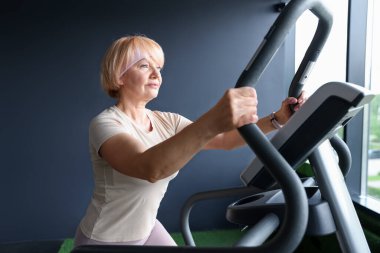 Son sınıf kadın spor salonunda eliptik makine eğitimi alıyor.