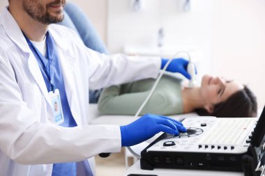 Sonograf klinikte kadının tiroid bezini ultrason taraması yapıyor.