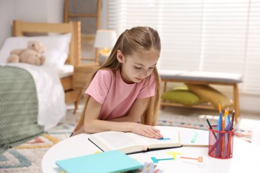 Disleksi. İçerideki masada kitap okuyan küçük kız.