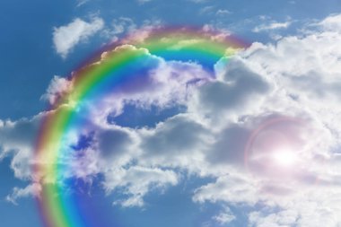 Mavi gökyüzünde parlak gökkuşağı güneşli bir günde bulutlarla