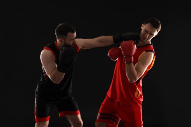 Siyah arka planda dövüşen boks eldivenli adamlar.