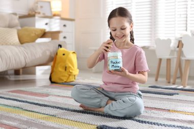 Kız evde cep harçlığını kavanoza koyuyor. Metin için boşluk