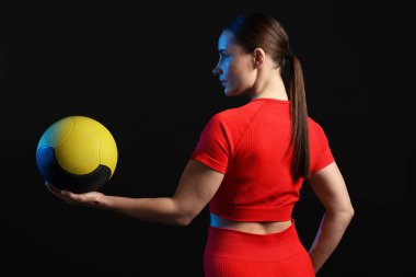 Siyah arka planda tıp topu olan kadın.